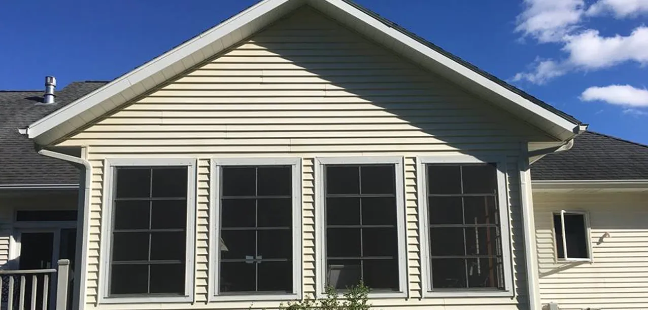 Cream vinyl siding and sunroom windows after soft washing